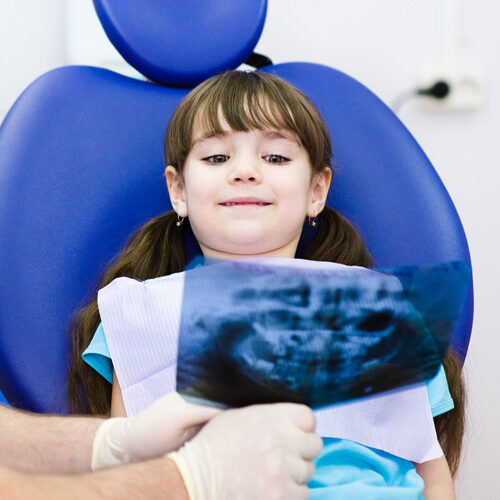 Dentist showing dental x-ray to young girl